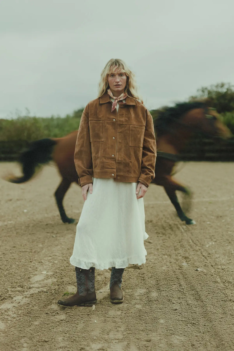 Eine Frau in einem Paar Westernstiefel von Durango vor einem galoppierenden Pferd